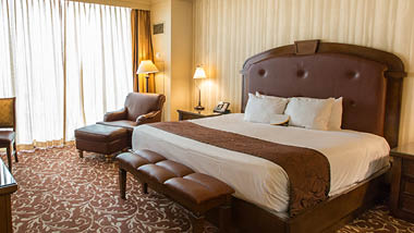 Picture of a hotel room containing a king-size bed, armchair and ottoman at Argosy Casino Spa in Riverside, Missouri.