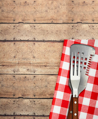 wood table bbq utensils and red and white check napkin