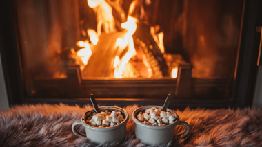 Two mugs with Hot chocolate in front of a fire place
