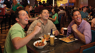 three guys in a bar eating and drikning beer