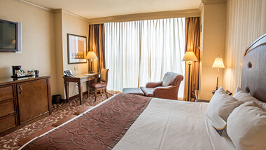 A king-sized bed, flat-screen TV, armchair desk and dresser inside a hotel room at Argosy Casino in Kansas City, Missouri.