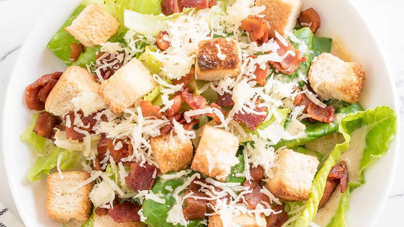 salad with cheese, bacon and croutons on marble countertop